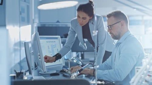 Chefingenieurin spricht mit männlichem Elektronikspezialisten, erklärt Dinge, er arbeitet an Comput