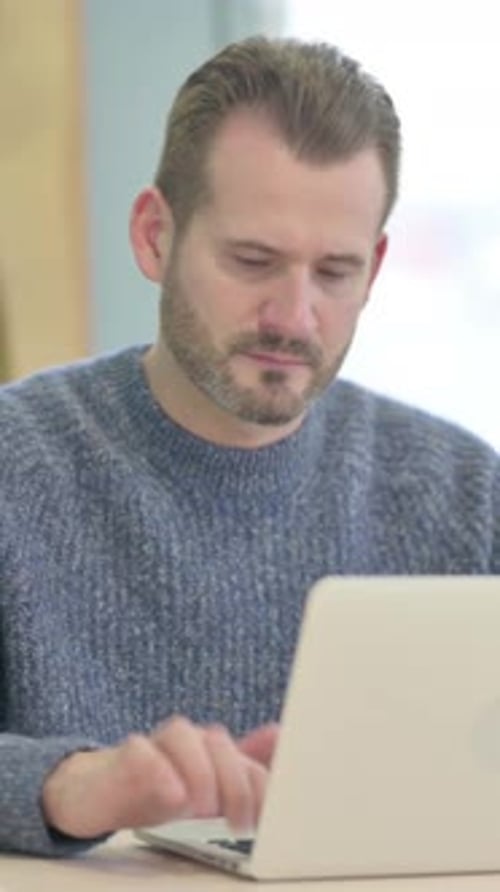 Middle Aged Man Looking at Camera while using Laptop, vertical video