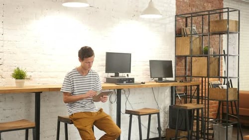 Casual Young Man Using Tablet in Office