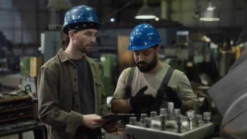 Male Plant Worker Explaining Work of Turning Machine to Colleague