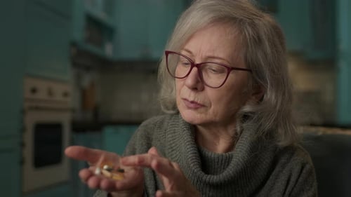 Senior Woman Examines Pills in Her Hand