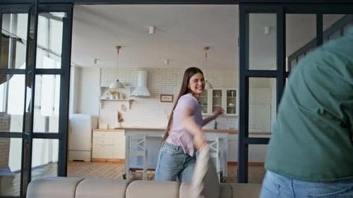 Playful Young Couple Having a Pillow Fight at Home