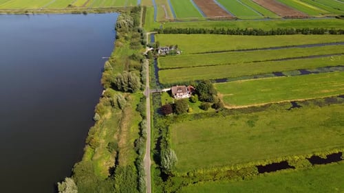 Aerial view of a rural landscape with central road water body irrigated fields and scattered houses