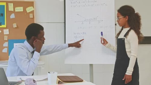 Student Presenting Math to Teacher in Classroom