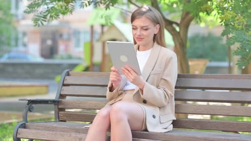 Young Woman Uses Tablet on Park Bench