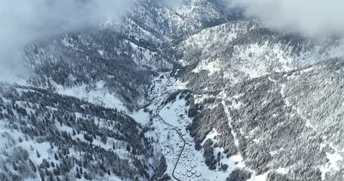 Snowy Trees and Houses from a Bird’s Eye View Through the Clouds – Majestic Winter Aerial Scene