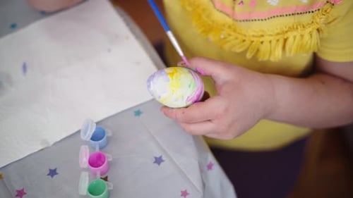 Kind im Vorschulalter malt Ostereier zu Hause in der Küche
