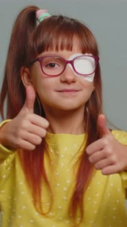 Smiling Girl with Eye Patch Gives Thumbs Up