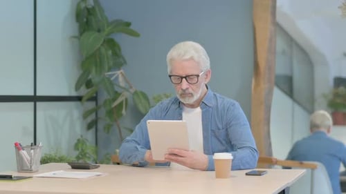 Senior Man Using Tablet Device at Desk