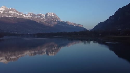 Ascending aerial towards the town of Sallanches and over the Passy lake early in the morning.