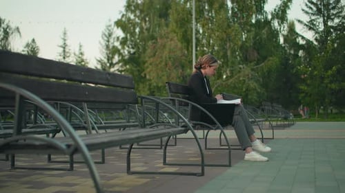Young Woman Working Outdoors with Folder and Laptop in Tranquil Park Setting