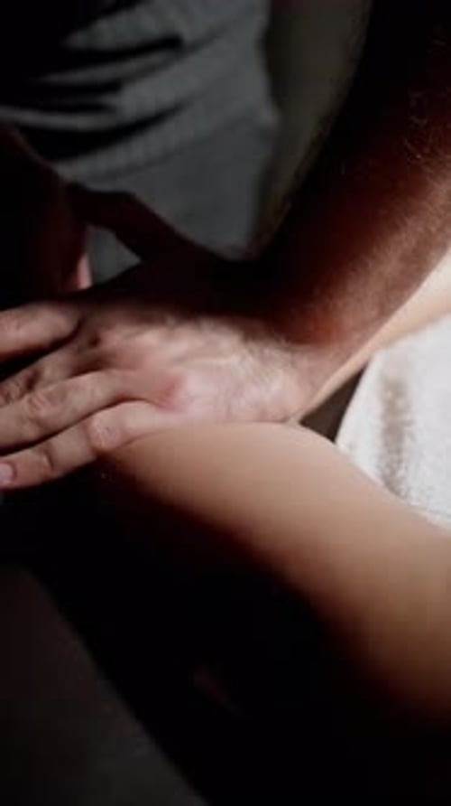 Massage therapist providing arm massage to client