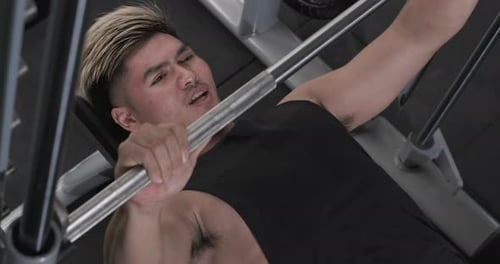 Man Bench Pressing Barbell in Gym