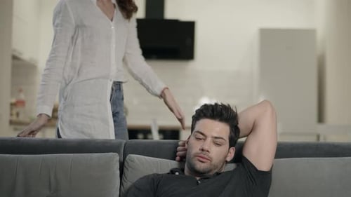 Man Relaxing on Couch with Wife Looking Over