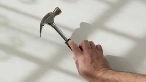 Shiny Metal Mallet with Black and Green Handle is Placed on White Surface Frame From Top to Bottom