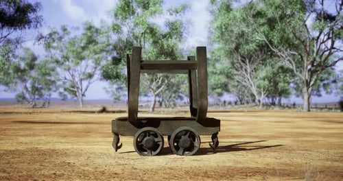 Metal Cart Sits on Dry Ground Surrounded By Tall Green Trees in Daylight