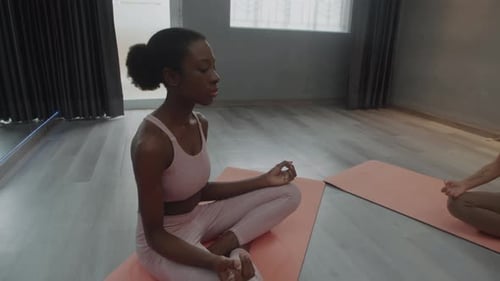 Sportswomen Meditating during Yoga at Fitness Studio