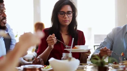Colleagues enjoying meal at restaurant together in daytime