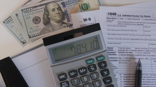 Close Up of Calculator and 1040 and W9 Individual Tax Form are Placed on Desk of American Citizen