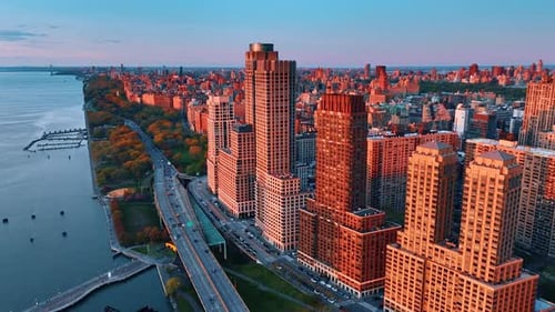 Buildings in New York panorama coated with soft orange light of setting sun.