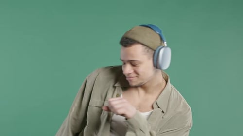 Happy Positive Man Listening Music Enjoying Dance with Headphones Green Studio