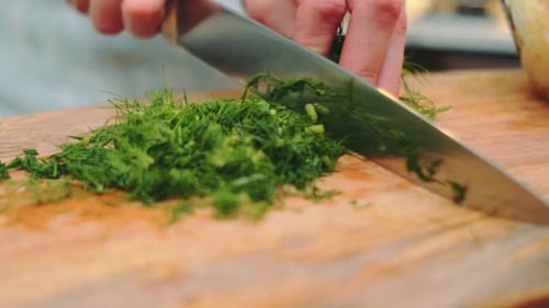 Cutting Dill with a Sharp Knife on a Cutting Board