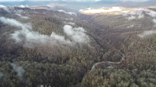 View of the Autumn Forest in the Mountains Through the Clouds