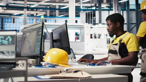 Un travailleur noir programme une chaîne d'assemblage robotique dans une usine de cellules solaires