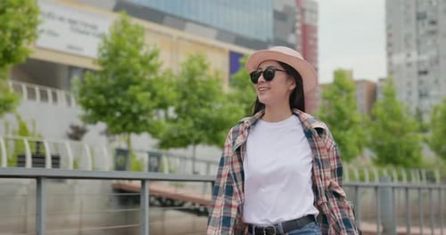 Young Asian Woman Wearing Casual Clothes with Backpack on the Back Walking at the City