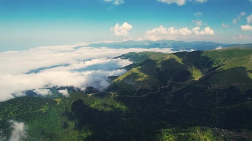 Mighty mountains with clouds. Green mountains and blue sky. Flight over the mountains.