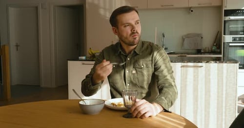 Man Eating Breakfast at Table in Sunny Kitchen
