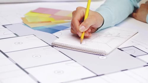 Designerin arbeitet an einem Blueprint-Projekt mit Notizbuch und Farbmustern