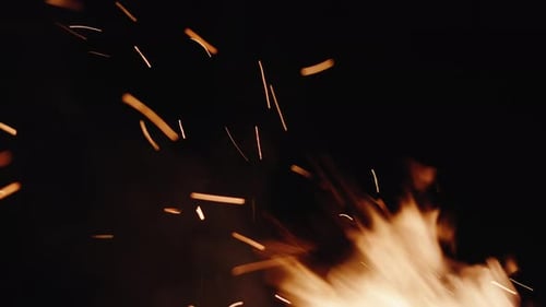 Extreme Nahaufnahme flackernder orangefarbener Flammen eines Lagerfeuers und der aufsteigenden Glut