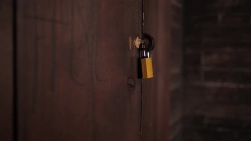 An Old Metal Door with a Padlock in a Dark Room of an Abandoned Building