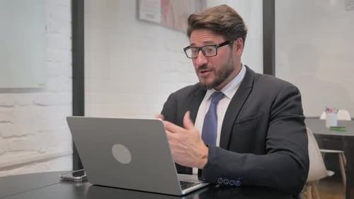 Man in Suit Talking on Laptop Video Call