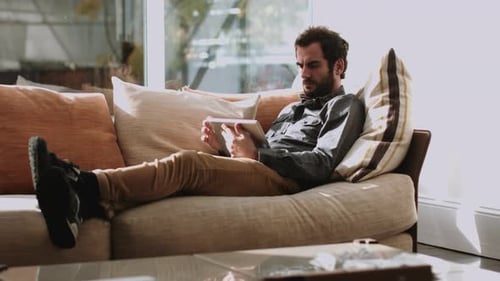 Man Relaxing on Couch Using Tablet Device