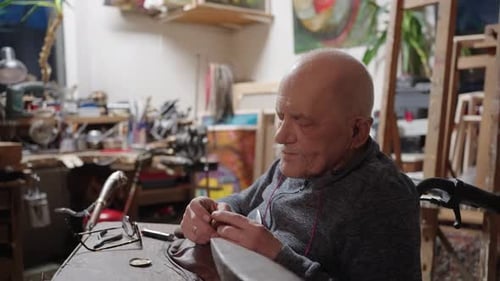 Senior Elderly Master Jeweler in Wheelchair Works in a Workshop