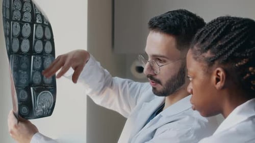 Male Middle Eastern Neurologist Discussing with Colleague MRI Scan Indoors