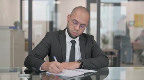Junger hispanischer Geschäftsmann schreibt Geschäftsbericht bei der Arbeit