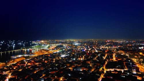 Glowing cityscape of the beautiful city at night. Illuminated shore and yachts on the waterscape.