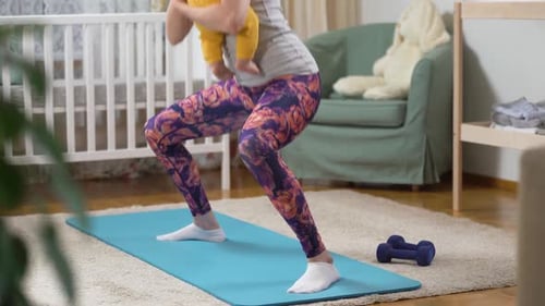 Woman Holding Baby Doing Squats in Nursery