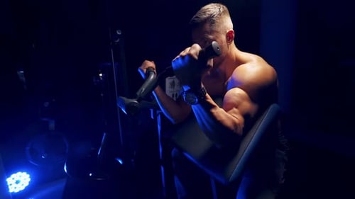 Young man training in the gym. Young strong focused fit muscular man training in the gym