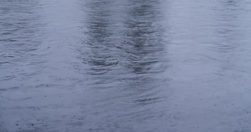 Wasseroberfläche bei leichtem Regen mit Regentropfen in Blue Hue. Speicherplatz kopieren