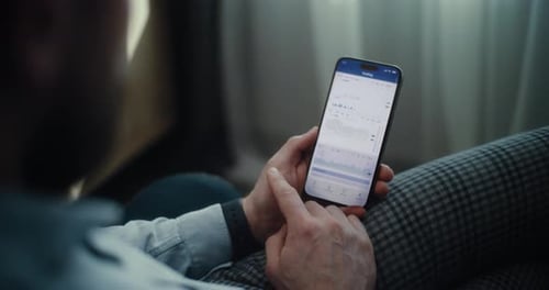 Close Up of Stock Exchange Broker Using Smartphone Monitoring Exchange Market Charts in Online