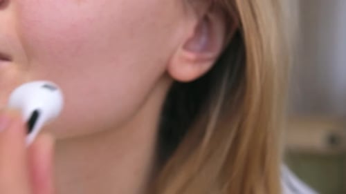 Close Up of Woman Inserting Wireless White Earphone Into Her Ear Listens to Music Footage