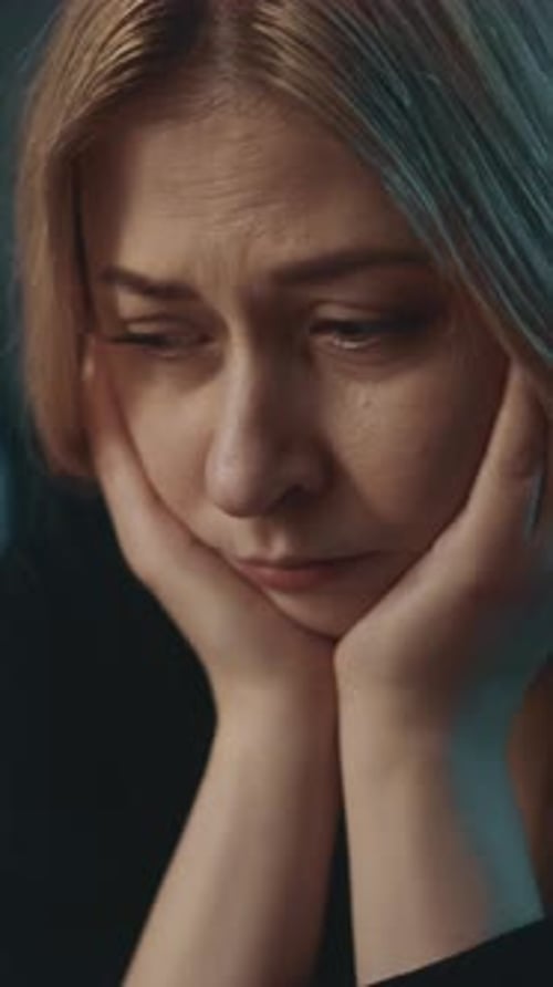 Distressed Woman With Hands on Face Looking Down