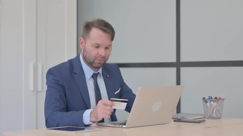 Man With Credit Card Looking Frustrated in Office