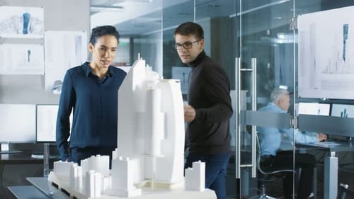 Two Young and Progressive Architectural Engineers Work on a Building Model that is Part of a Big Ne