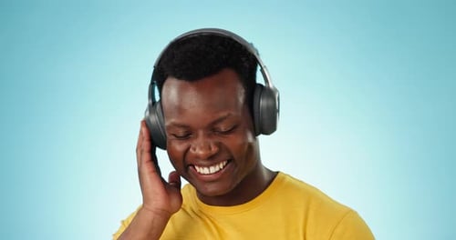 Happy black man, headphones and dancing to podcast, music or playlist against a studio
