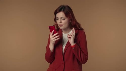 Medium Isolated Video of a Woman Holding a Smartphone in Her Hand Crossing Fingers Waiting for the